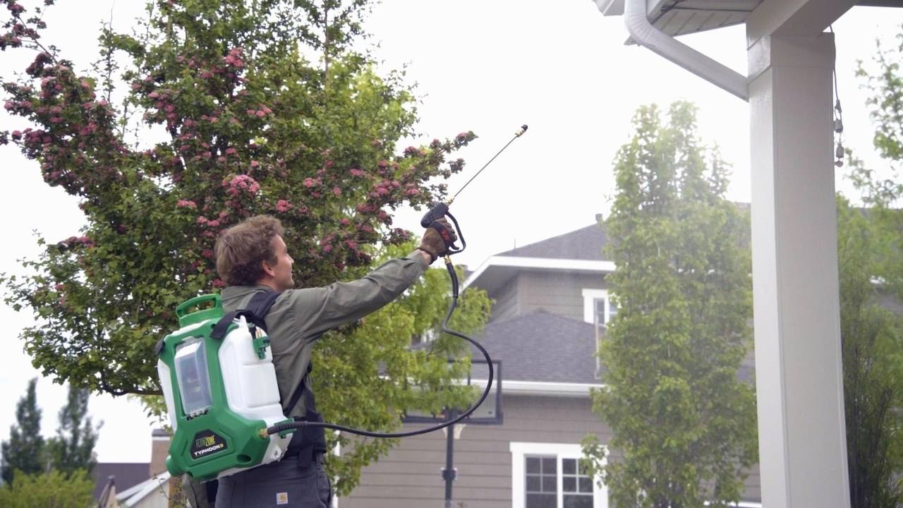 Pest control technician spraying eaves — service in Wasatch County / Wasatch Back